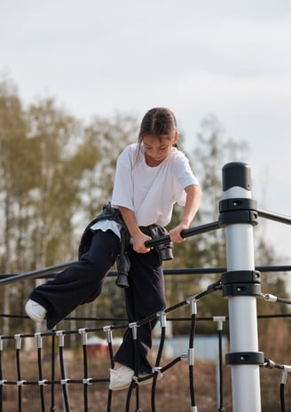 Fille grimpant sur une structure Kenguru Pro Kids Active Play en extérieur.