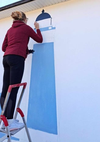 Artiste en train de peindre une fresque bleue sur un mur de maison 