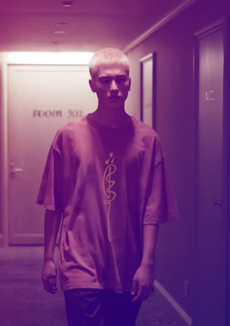 male model in oversized talisman T-shirt by FuluTee walking down dimly lit hallway with surreal, dreamy lighting.