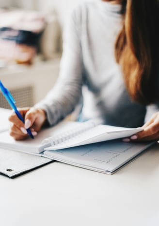 Woman is writing something on a notebook