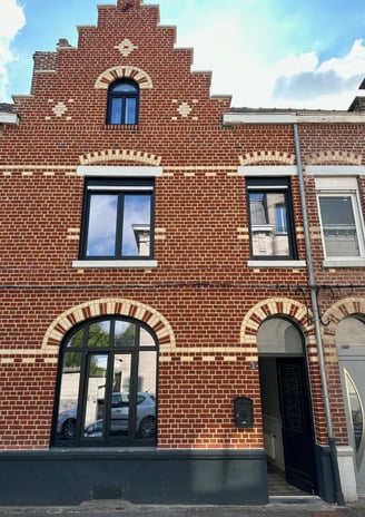 Maison en briques rouge avec fenêtres en aluminium noir