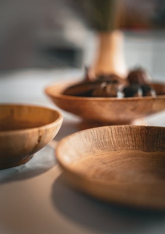 Composition artistique mettant en avant plusieurs bols et plats en bois faits main, posés sur une ta