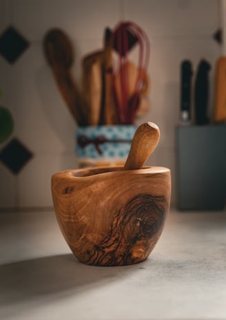 Mortier en bois massif artisanal accompagné de son pilon, posé sur un plan de travail dans une cuisi