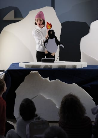 a woman in a pink hat and a penguin on a stage