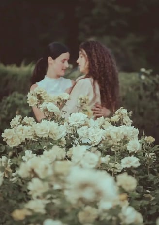 "Pareja lesbiana con flores de rosa blanca, celebrando su compromiso en una boda gay."