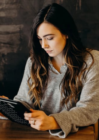 a woman sitting at a table with a laptop and a tablet