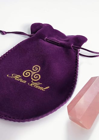 a purple velvet pouch bag with a crystal point of pink quartz