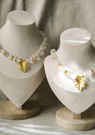 two necklaces with gold leaf charms on them