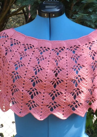 cache épaule crocheté dans un fil coton couleur vieux rose posé sur un mannequin de couleur bleu  