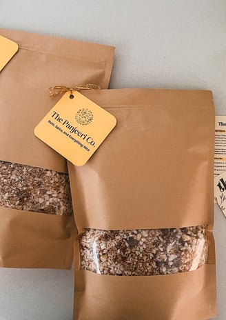 Two sealed, recyclable brown paper bags filled with handcrafted subcontinental granola (Panjeeri).