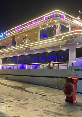 a boat docked at night with a boat in the background
