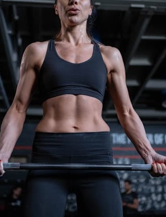 een vrouw in de sportschool die aan het gewichtheffen is op de achtergrond is een sportschool te zien