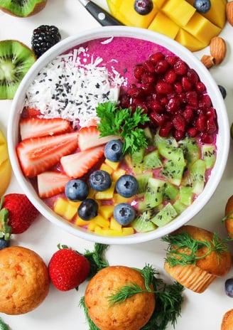 witte achtergrond met verschillende soorten fruit soorten met in het midden een schaal yoghurt met fruit erin