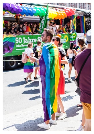 Ein Mann trägt eine Regenbogenflagge bei der Christopher Street Day Parade in Berlin.