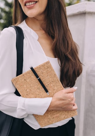 a woman in a white blouse and black pants carrying a notebook with pen