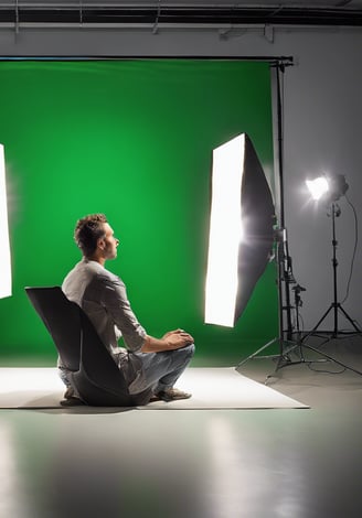 a man sitting in a chair in front of a green screen