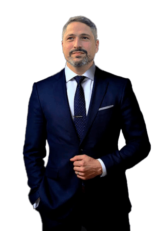 Homem branco de barba grisalha sorrindo vestindo terno e com gravata azul marinho