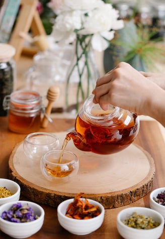 Woman brewing herb tea and white flowers on the table