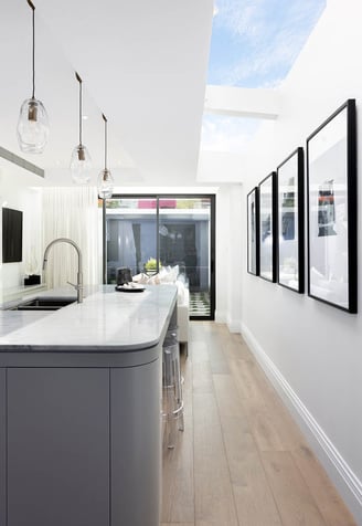 Stylish kitchen island with skylight above, oak flooring, contemporary interior design, modern art