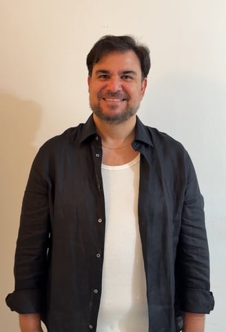 a man in a black shirt and jeans standing in front of a wall