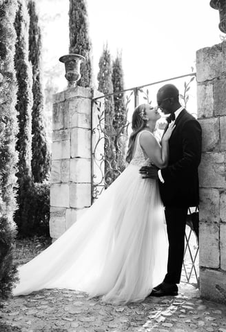Black and white portrait of newlyweds in a French garden, bride nestled against the groom
