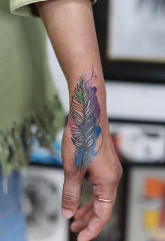 Blue and purple watercolor feather tattoo at Dudo’s Tattoos Hyderabad