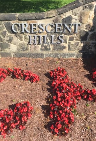 Crescent Hills stonework sign and red flowers spelling C H