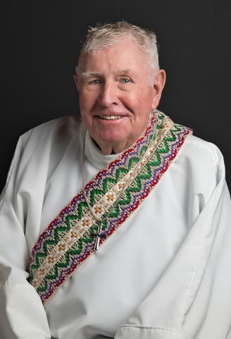 a man in a white shirt of church clergy and a tie dye on his neck 