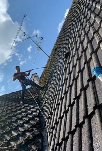 Artisan couvreur en intervention sur une toiture, effectuant un nettoyage haute pression à Belfort, équipé de harnais de sécu