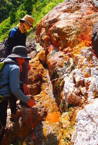 two people standing on rocks with a backpack