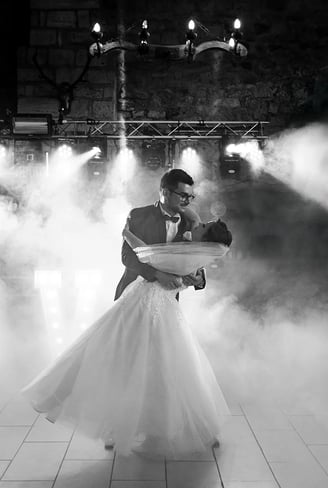 Marié portant sa femme dans ses bras lors de leur ouverture de bal, entourés de fumée et lumières.