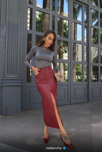 a woman in a grey top and red skirt