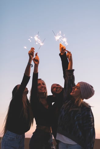 a group of friends holding sparklers in the sky