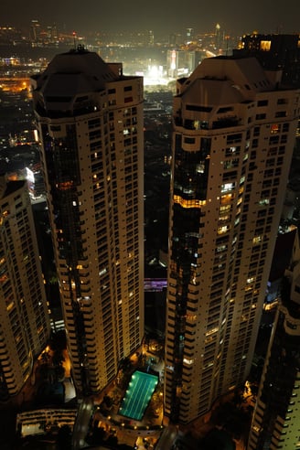 Night aerial view of twin towers in bangkok with pool below, By ACAT Photos
