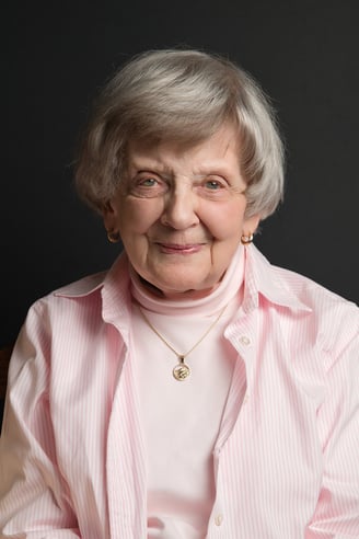 an old woman in a pink shirt and a necklace and earrings