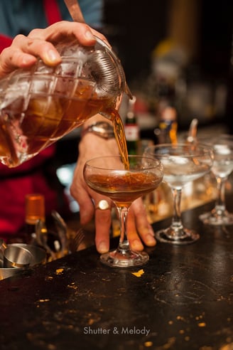Ein Mann schenkt einen Cocktail in ein Glas ein.
