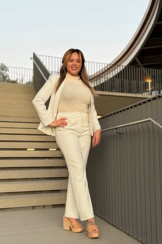 a professional woman doctor in a white suit and heels standing in front of a staircase, ascending