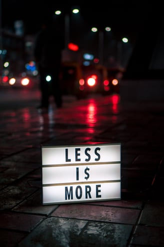 a sign that says less is more at night on a wet street