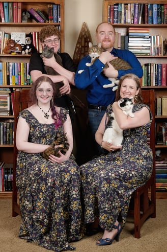 a family portrait of parents and kids with four cats on their arms