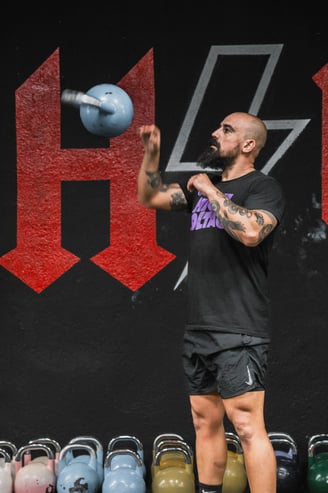 a man in a black shirt and shorts is holding a kettle kettlebell