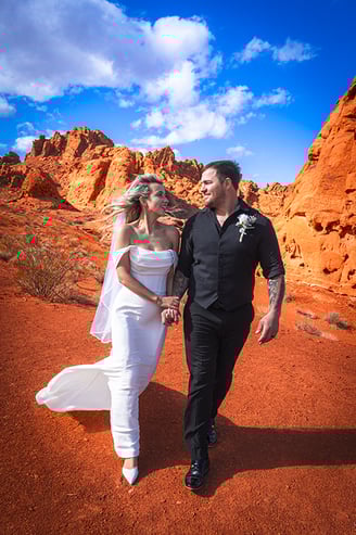 a bride and groom walking through a desert