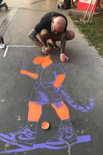 Sérgio Astral pintando sua obra "Onças Humanas" com a técnica de stencil no Centro Cultural.