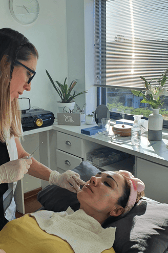 a woman getting a facial lift from a woman in a white shirt Dra. Flavia Ward