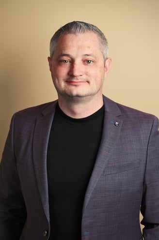 a man in a suit and black shirt with indoor lighting