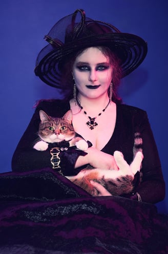 a woman in a witch costume wearing a black hat and holding a cat