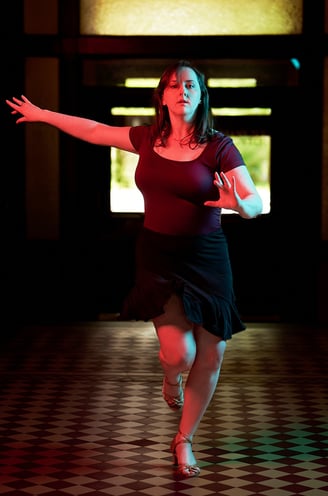 a woman in a black dress dancing in a dark room