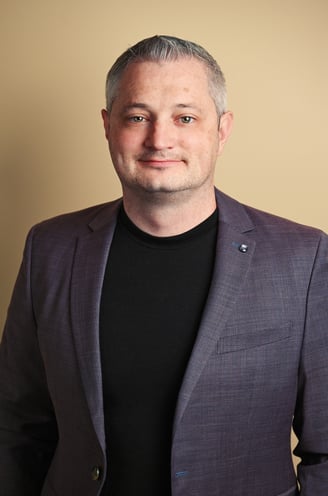 a man in a suit and black shirt with indoor lighting