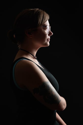 a woman with tattoos on her arm showing her profile with dramatic lighting