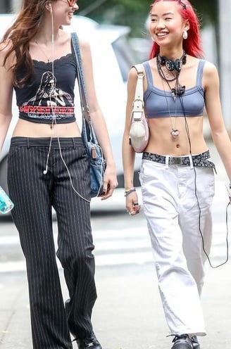 Modelo feminino com camiseta listrada, calça de moletom, jaqueta de couro e botas.