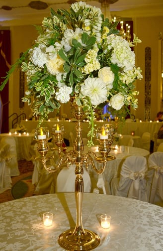 a tall gold fancy candle holder with candles and flower